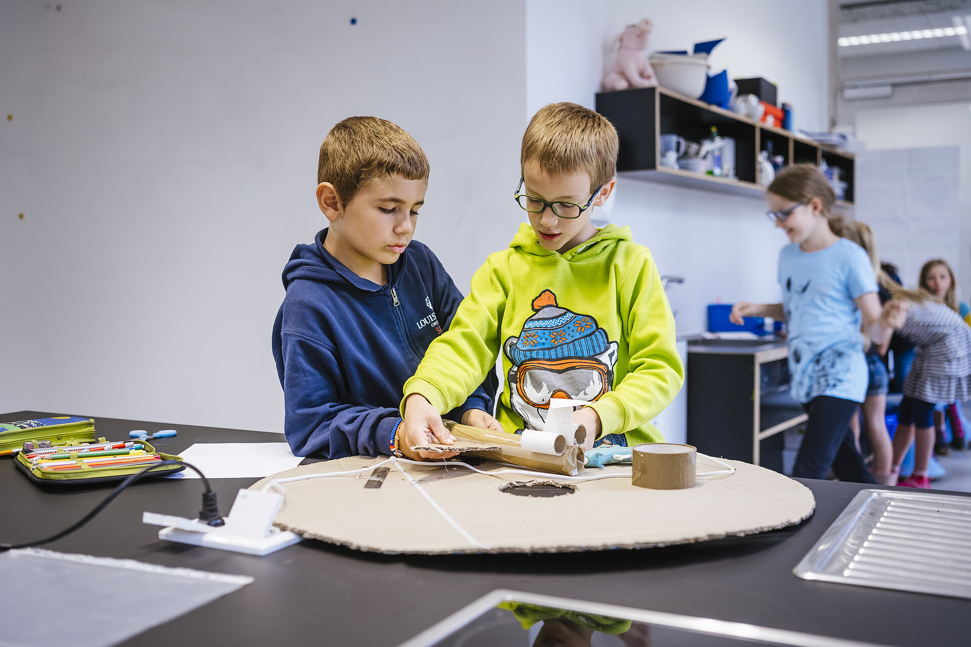 Zwei Kinder arbeiten gemeinsam mit Holz und Karton und bauen ein Flugzeug